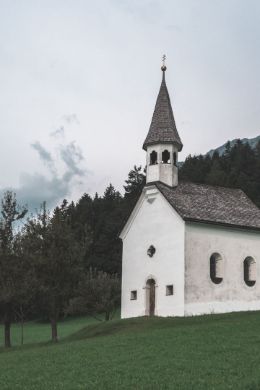 Weiße Kapelle auf einer Wiese vor einem Wald
