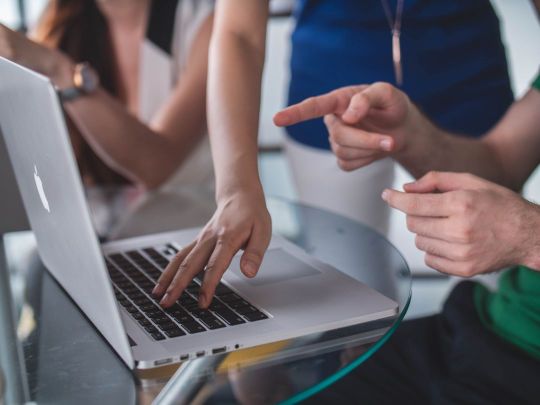 Mehrere Personen, die auf einen Laptop zeigen