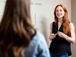 Dozentin steht vor weißer Tafel